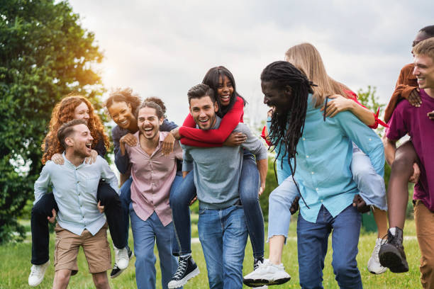 Young diverse friends having fun outdoor laughing together - Focus on center african girl face stock photo