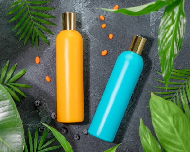flaconi cosmetici arancioni e blu senza etichetta nelle foglie verdi centrali - merchandise luxury still life spa treatment foto e immagini stock