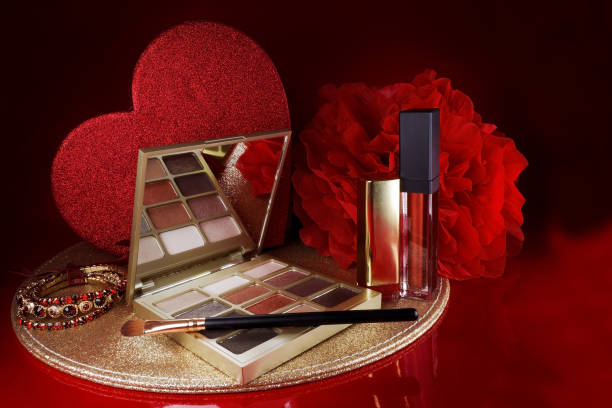 Cosmetics on a red background. There are lipstick, eyeshadow, powder, blush, eyeliner,