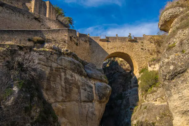 Photo of The Old Bridge (Puente Viejo) and the Ronda Gorge (Tajo de Ronda) on the Guadalevin River. Andalusia, province of Malaga, Spain