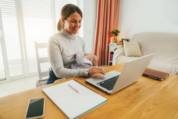 istock Young mother working at home while feeding her infant son - Smart working and family concept - Focus on mom face 1460775387