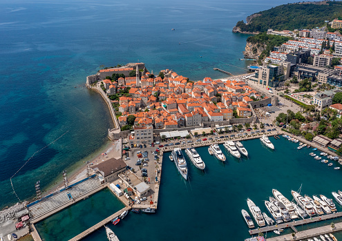 Aerial view of walled old town of Budva city.  Pier with moored yachts and boats. Adriatic sea, Montenegro