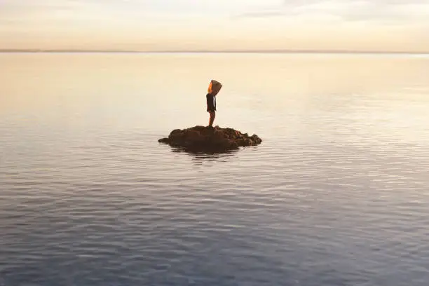 man with paper bag on his face does not accept his shipwrecked condition on an island, abstract concept