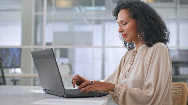 Woman sitting in the office and typing on her laptop