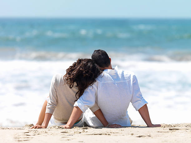 istock woman leaning head on man's shoulder at beach 146077919