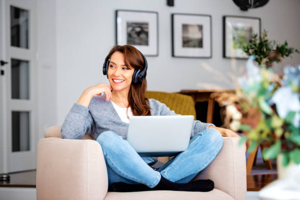 istock Attractive woman relaxing at home and using earphone and laptop 1460781040