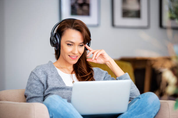 istock Attractive woman relaxing at home and using earphone and laptops 1460781094