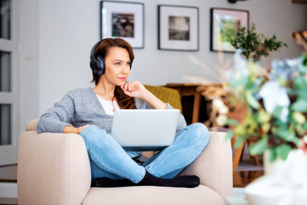 istock Attractive woman relaxing at home and using earphone and laptops 1460781110