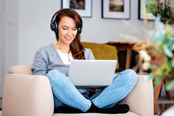 istock Attractive woman relaxing at home and using earphone and laptops 1460781129