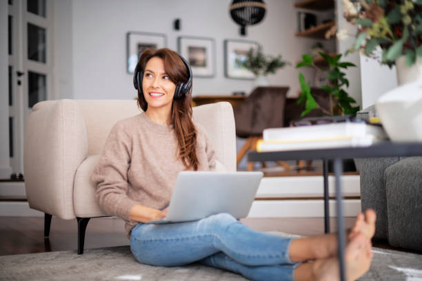 istock Happy woman wearing headphone and using laptop while relaxing at home 1460781214