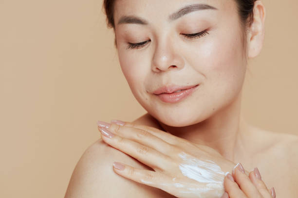 istock relaxed modern woman with hand cream on beige background 1460781699