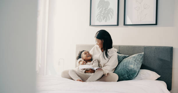 istock Story time, little girl laughing with her mom while reading a book 1460783149
