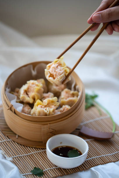hand taking chinese dumpling with wooden chopsticks