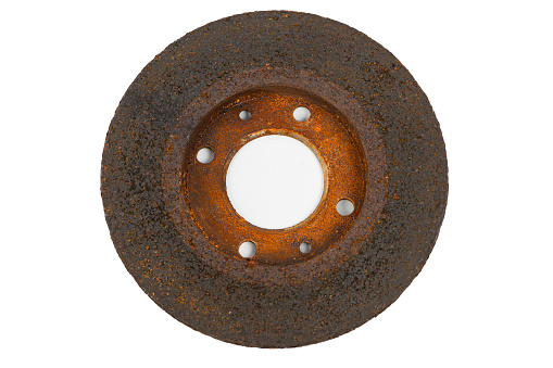 Old rusty and damaged brake disc studio shot isolated on white. A disc brake is a uses calipers to squeeze pairs of brake pads against a disc to create friction. Damaged disc brakes have to be replaced.