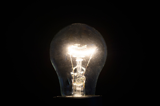 Old incandescent light bulb studio shot isolated on a black background.