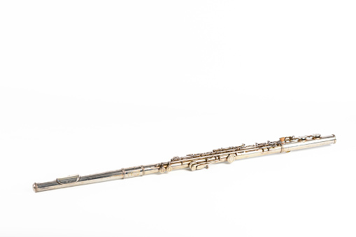 Western concert flute transverse woodwind metal musical instrument studio shot isolated on a white background. The flute has some patina marks.
