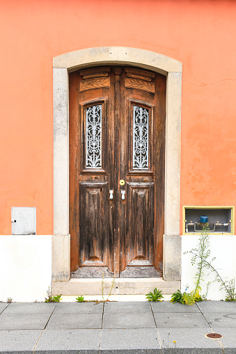 Old wooden door with wrought iron door knockers on pink facade in Lisbon, Portugal