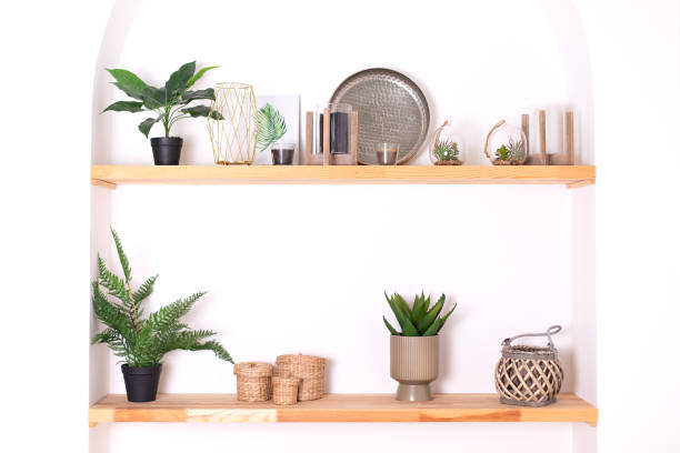 istock Modern composition of wabi sabi interior with shelf with stylish home decoration. Boho interior of living room and wooden shelves with elegant decor, vase, green houseplants in pots and candles. 1460791884
