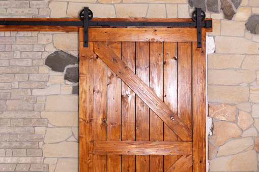Sliding barn wooden door in indoors. Sliding old Barn Door in modern room. Rustic farm wood sliding barn style door at home.