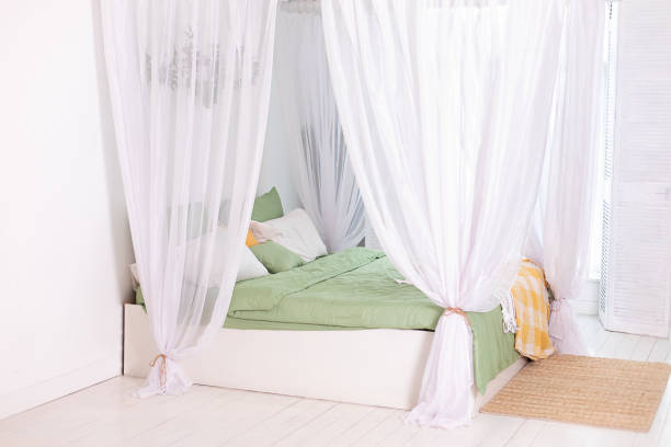 istock Modern white bedroom in Skandinavian style with bed with flowing white curtains. Interior boho design bedroom with comfortable bed with pillows, copy space. 1460792112