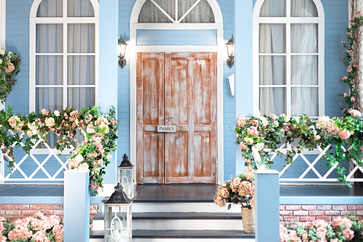 House entrance staircase at home decorated for easter. Wooden porch of house with different flowers. Terrace of summer house. Spring design home with bloom flowers and decoration lanterns on steps.