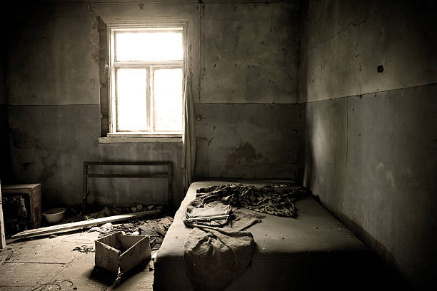Inside abandoned house. View on messy bed and window. Grunge scene.