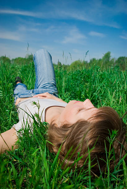 istock beautiful young woman relaxing in the grass 146079661