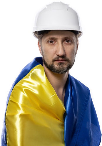 Portrait of a worker with a Ukrainian flag on his shoulders. The man with a work helmet on his head. Portrait of a man on a white background.