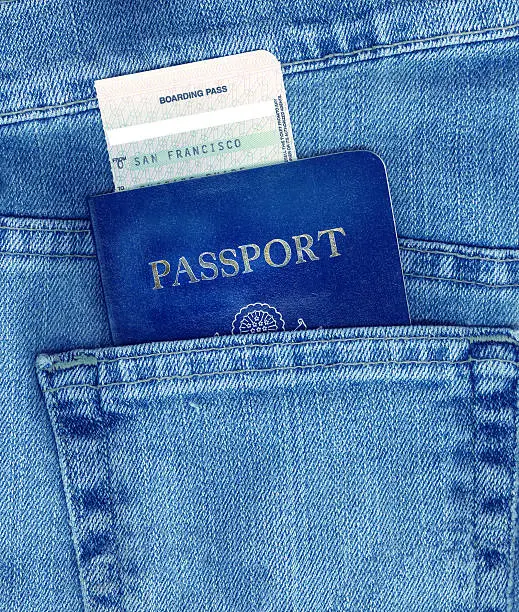 Passport and boarding pass in back pocket of blue jeans.