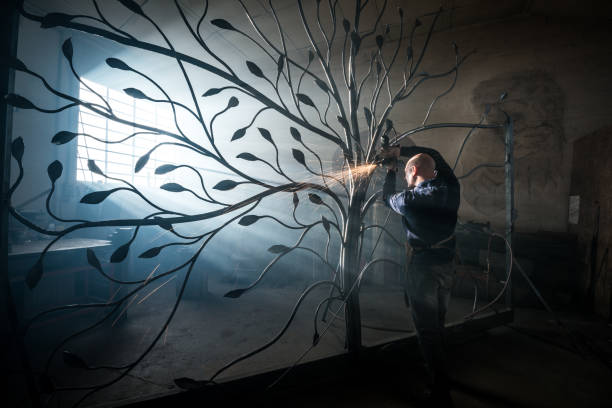 Blacksmith artist working in his smithy studio creating a gate-tree stock photo
