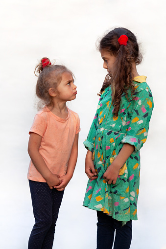 Side view of two little girls confront each other, isolated on white