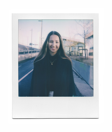 Instant photo print of a fashionable young businesswoman in the city on a sunny winter day. Photograph taken with an instant film camera.