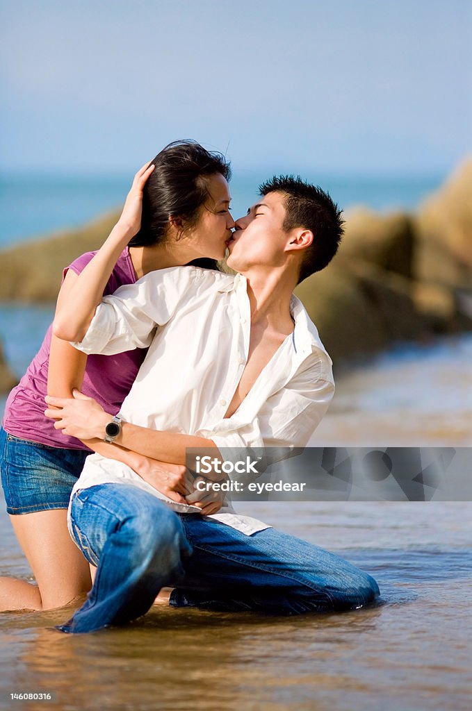 Amoroso jovem Casal a beijar enquanto squating pela praia - Royalty-free Ao Ar Livre Foto de stock