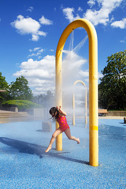 Child running in water park during early summer. Little girl having fun.