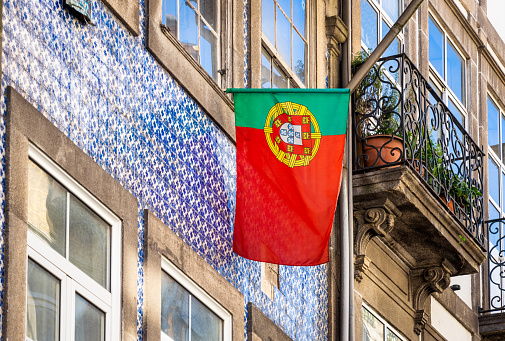 A Portuguese flag on the tiled exterior of a traditional apartment building in the city of Porto.