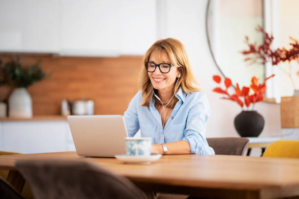istock Attractive woman with earphone using her laptop at home 1460807892