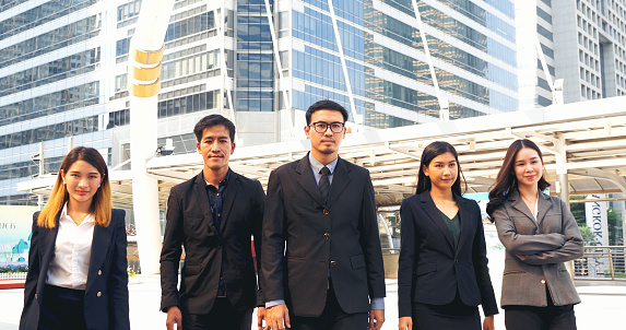 Portrait Group of businesspeople arms crossed smiling look at camera in modern city background. Happy Businessman, businesswoman teams partnership. Business people teams positive teamwork standing.