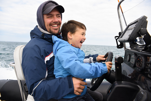 father and son driving a boat at sea