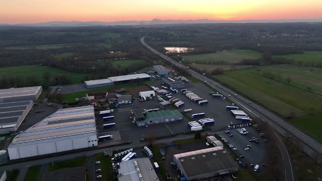 Aerial view of goods warehouses and logistics center in industrial city zone at sunset