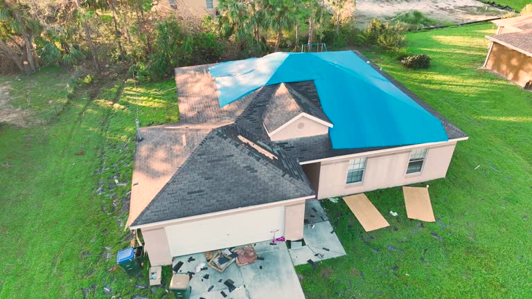 Top view of leaking house roof covered with protective tarp sheets against rain water leaks until replacement of asphalt shingles. Damage of building rooftop as aftermath of hurricane Ian in Florida