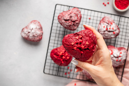 closeup heart shaped red velvet cupcake in female hand. Cooking with love concept. cropped image