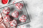 heart shaped red velvet cupcakes with sprinkles on a cooling rack