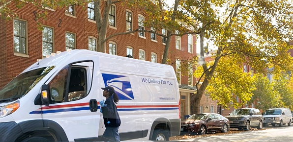 Female poatal worker is entering truck. The photo was taken on S Sharp Street, Baltimore 11/02/2022