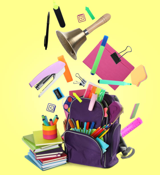 istock Backpack, school bell and different stationery flying on yellow background 1460820009