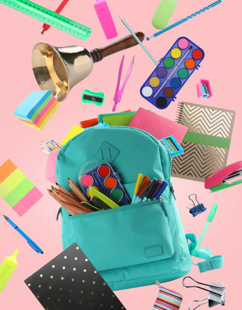 istock Turquoise backpack, school bell and different stationery flying on pink background 1460820096