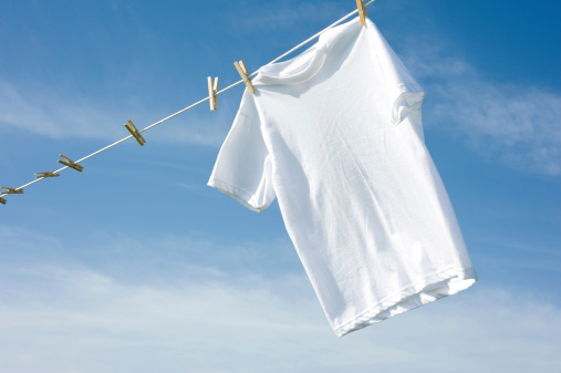 A plain white T-shirt hanging on a clothesline on a beautiful, sunny day, add text or graphic to shirts or copy space