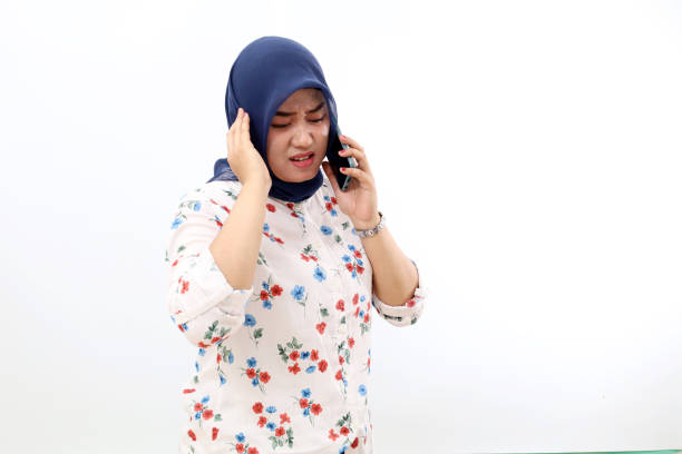 femme musulmane asiatique stressée debout tout en parlant au téléphone. isolé sur fond blanc - hearing aid isolated technology healthcare and medicine photos et images de collection