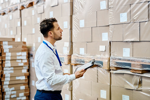 Boxes, logistics and man on tablet for warehouse, storage or package management in supply chain industry. Person on digital technology, e commerce and distribution stock check for his online business