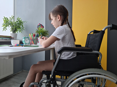 Disabled girl in wheelchair draws picture. Disabled child and hobby drawing