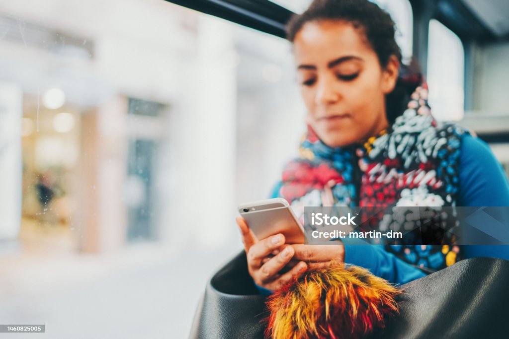 Mixed race woman in the bus typing on smartphone Sportswoman traveling in bus is checking social media on smartphone Mode of Transport Stock Photo
